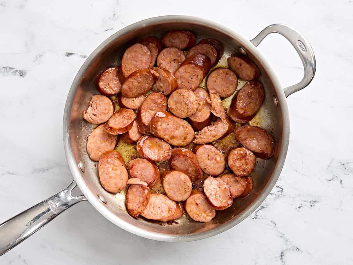 Andouille sausage cooking in a skillet.