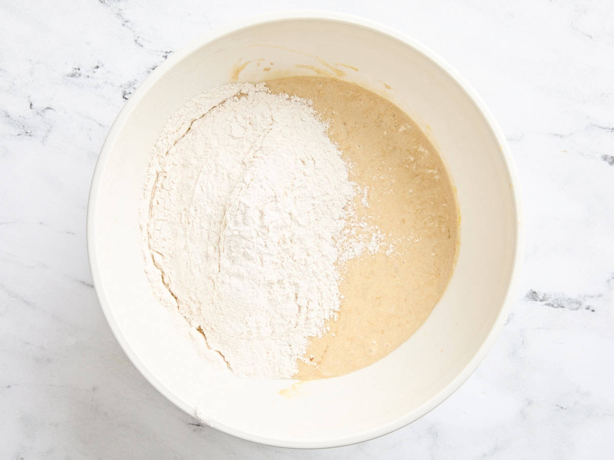 The dry ingredients for banana muffins added to the wet ingredients in a bowl.