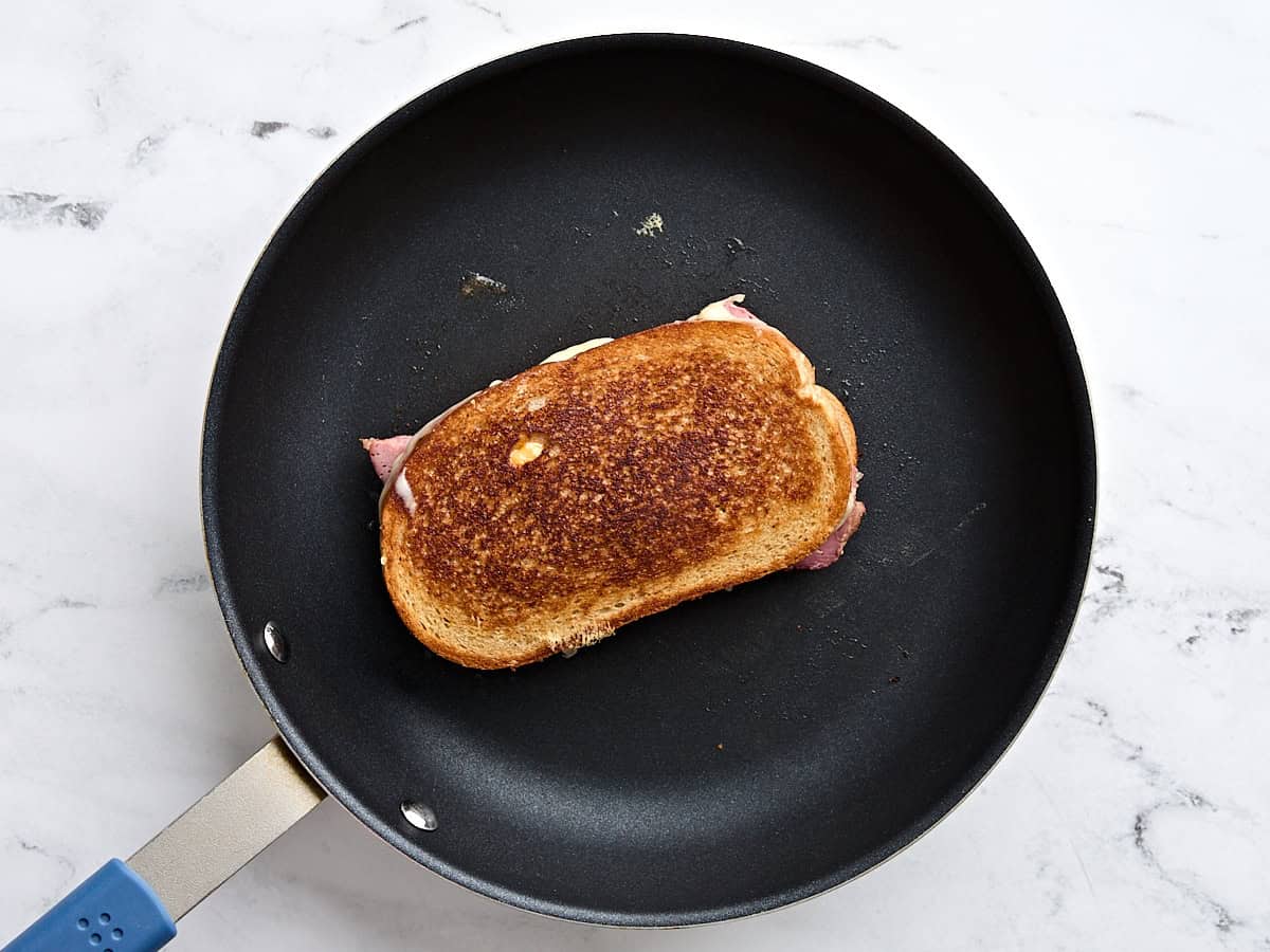 A reuben sandwich toasting in a skillet on the stove.