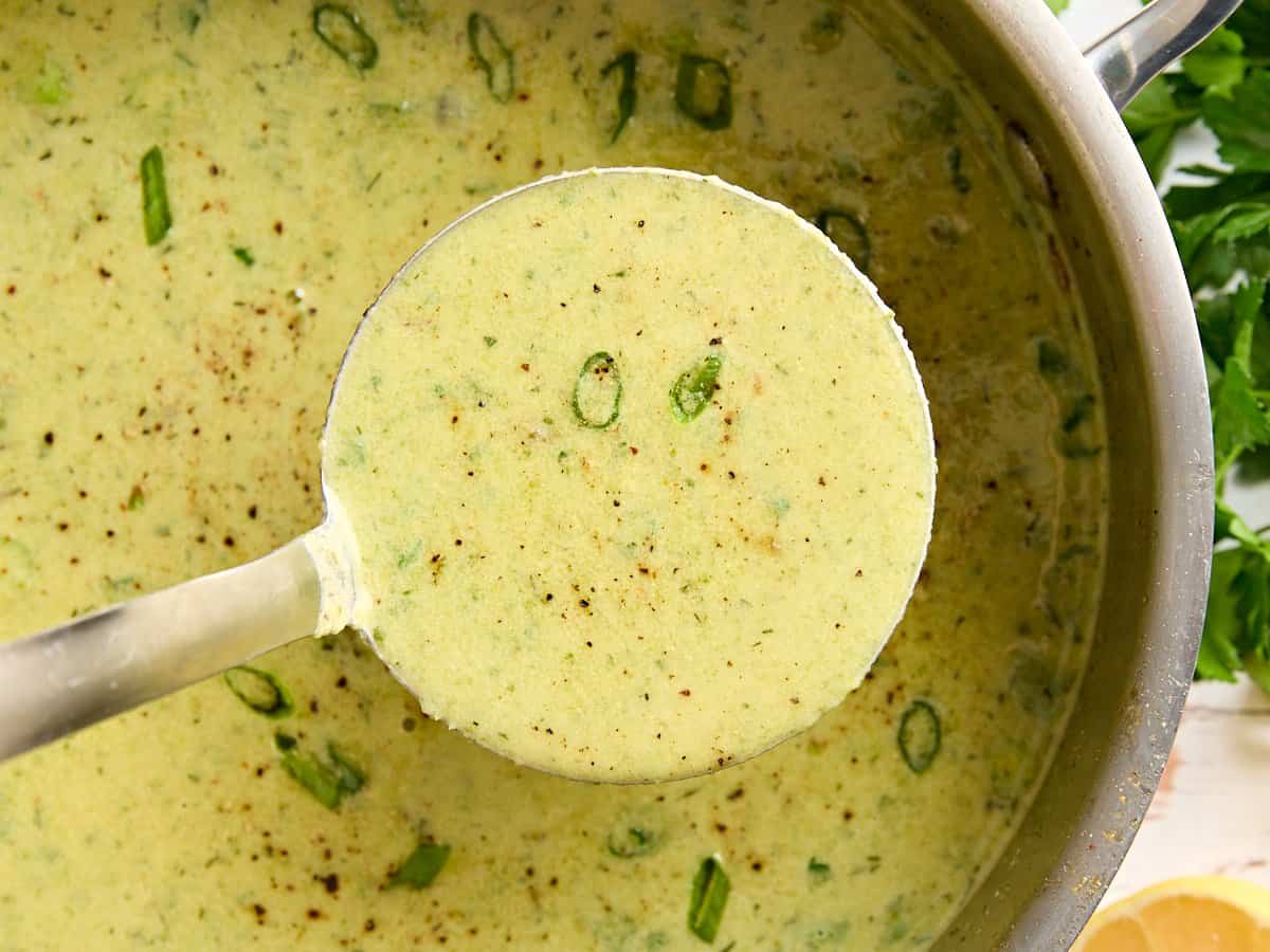 Overhead close up of asparagus soup in a sauce pot with a ladle.