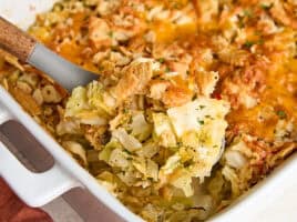 A serving spoon taking some cabbage casserole from a casserole dish.