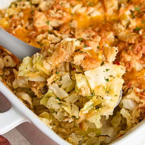 A serving spoon taking some cabbage casserole from a casserole dish.